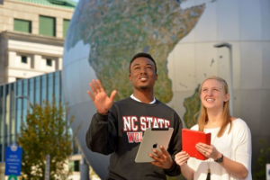 male and female student in front of a globe