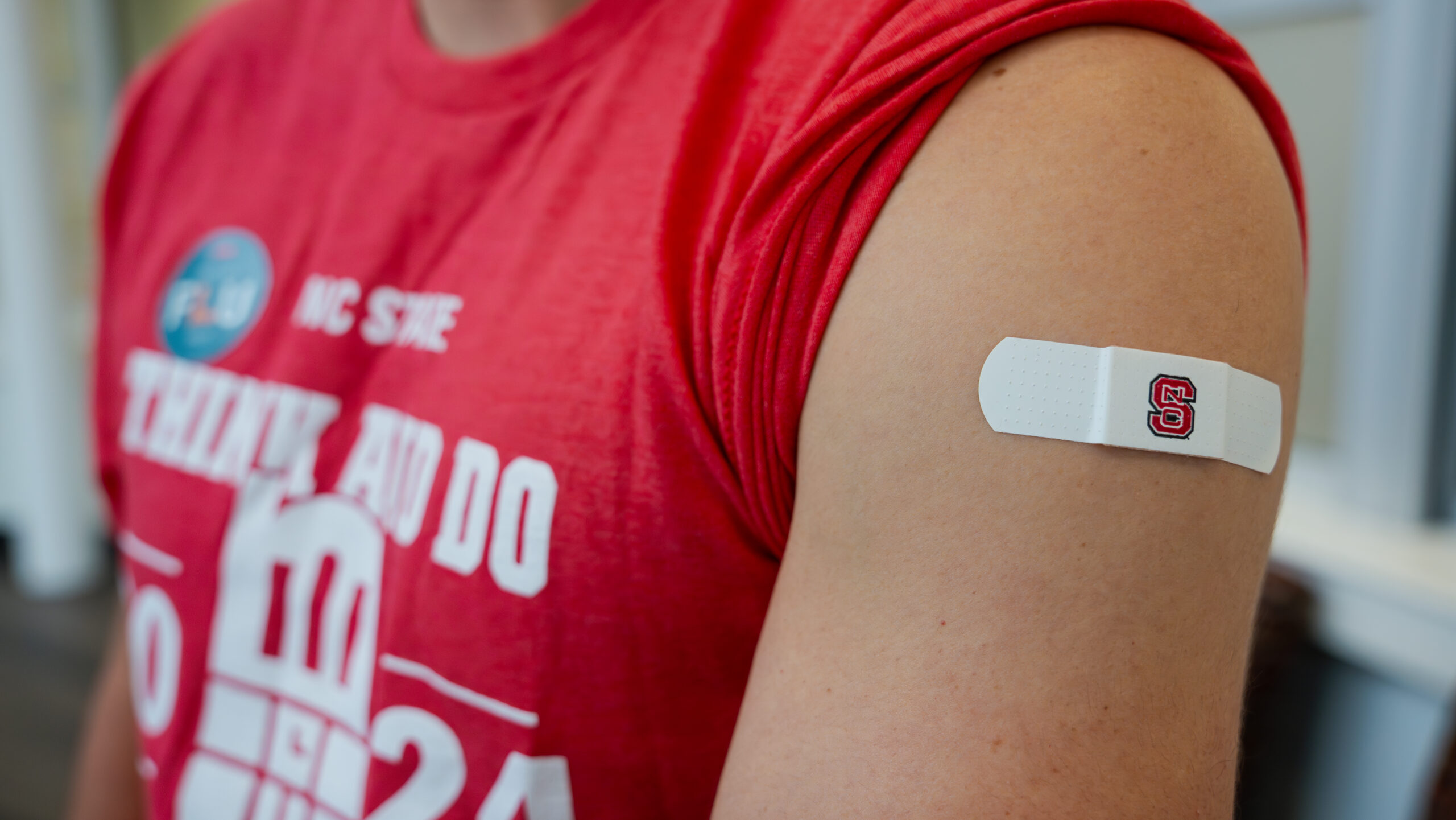 An arm with a white NC&#160;State branded bandage